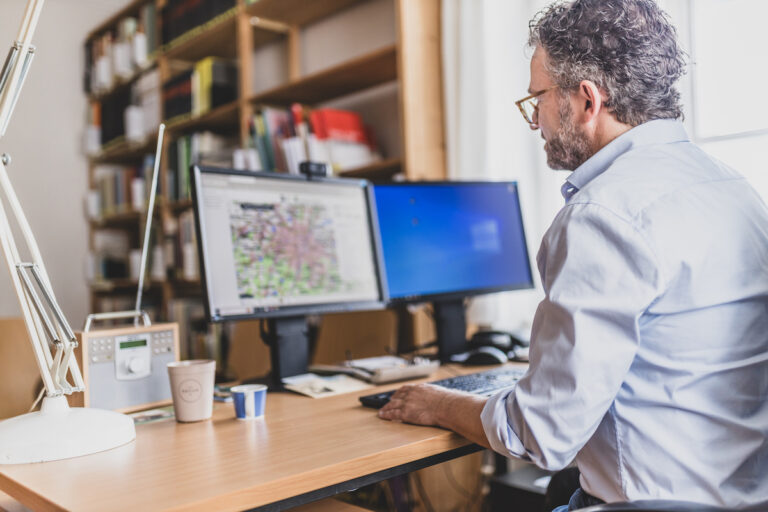 Thomas Büttner an seinem Arbeitsplatz, auf einem Bildschirm ist die Kulturlandschaftsdatenbank geöffnet.